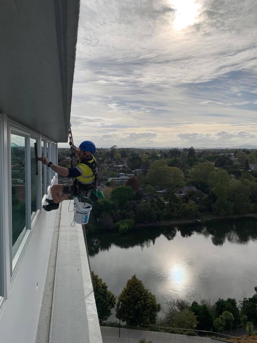 Abseiler cleaning windows looking over river
