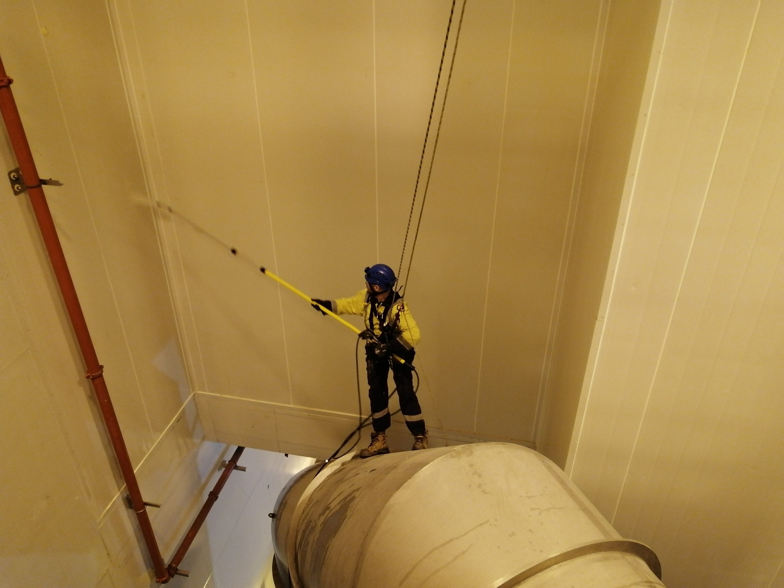 Industrial abseiler using extension waterblaster to reach difficult access areas