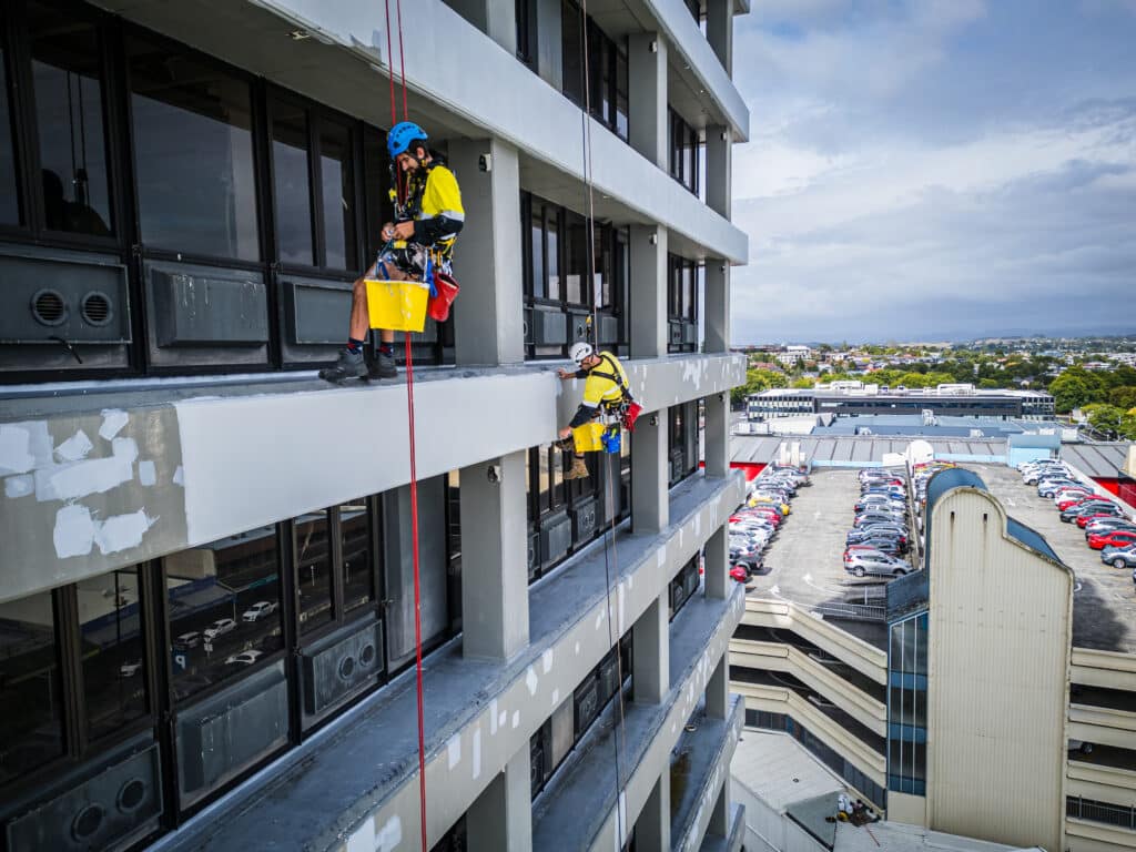 Connect Access rope access technicians performing exterior painting and maintenance on Mistry Tower in Hamilton, suspended by safety ropes and using industrial abseiling techniques to safely access the building façade.