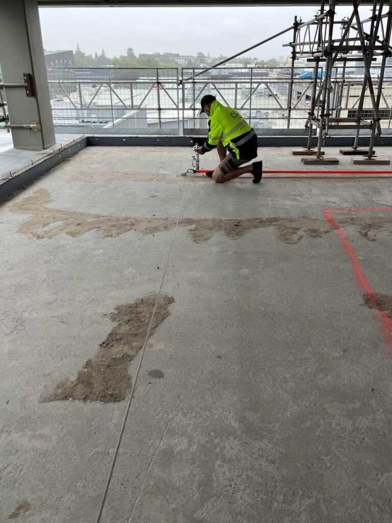 A Connect Access technician installs a safety rope's anchor system inside a building under construction
