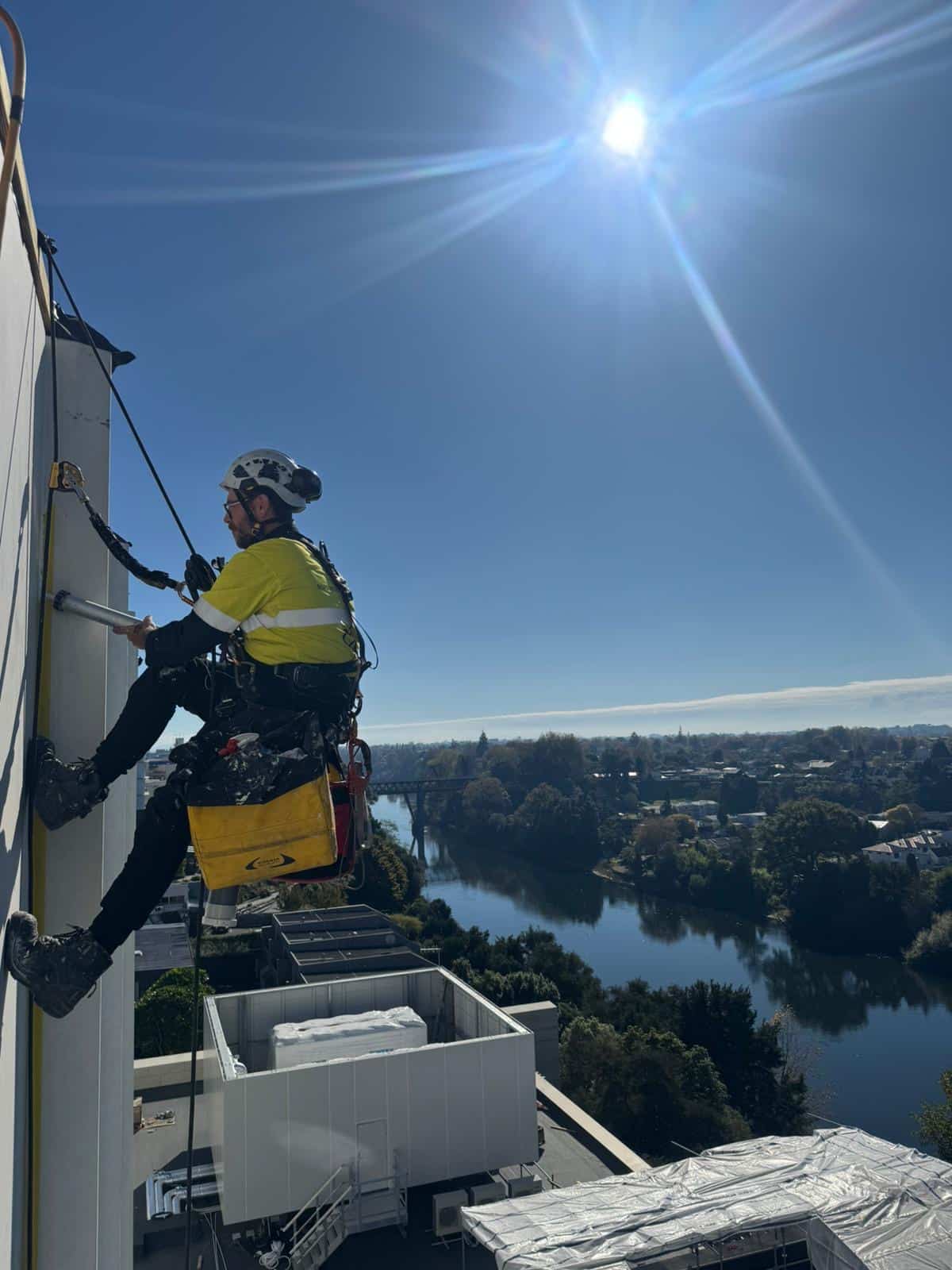 An IRATA-certified rope access technician working on a commercial building exterior.