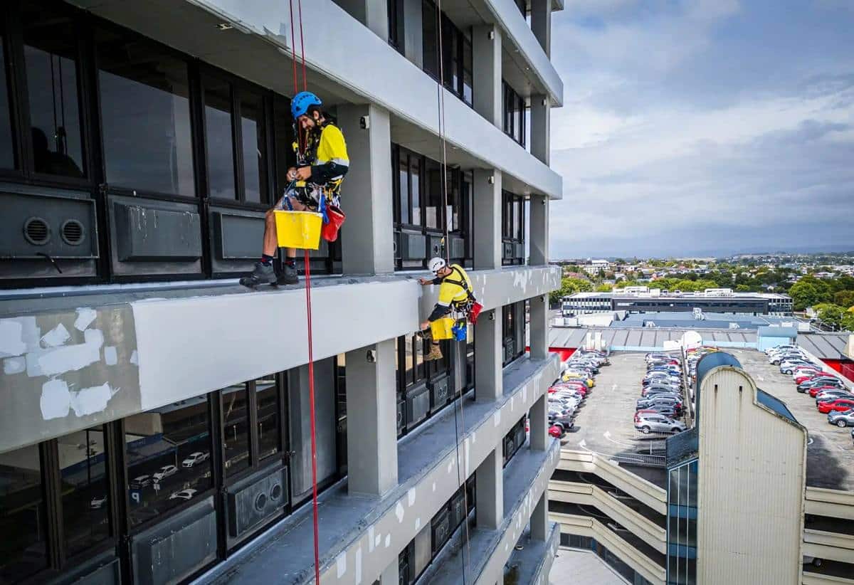 Connect Access rope access technicians do exterior painting and maintenance on Mistry Tower in Hamilton, suspended by safety ropes and using industrial abseiling techniques to safely access the building façade.