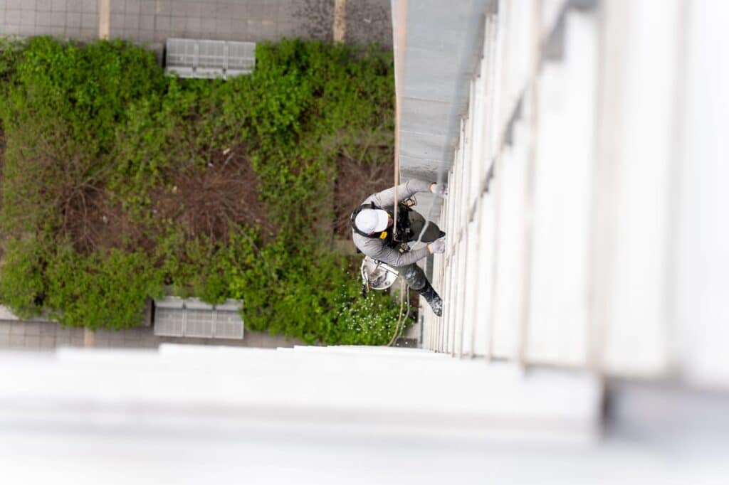 View from above of an industrial abseiler cleaning a window