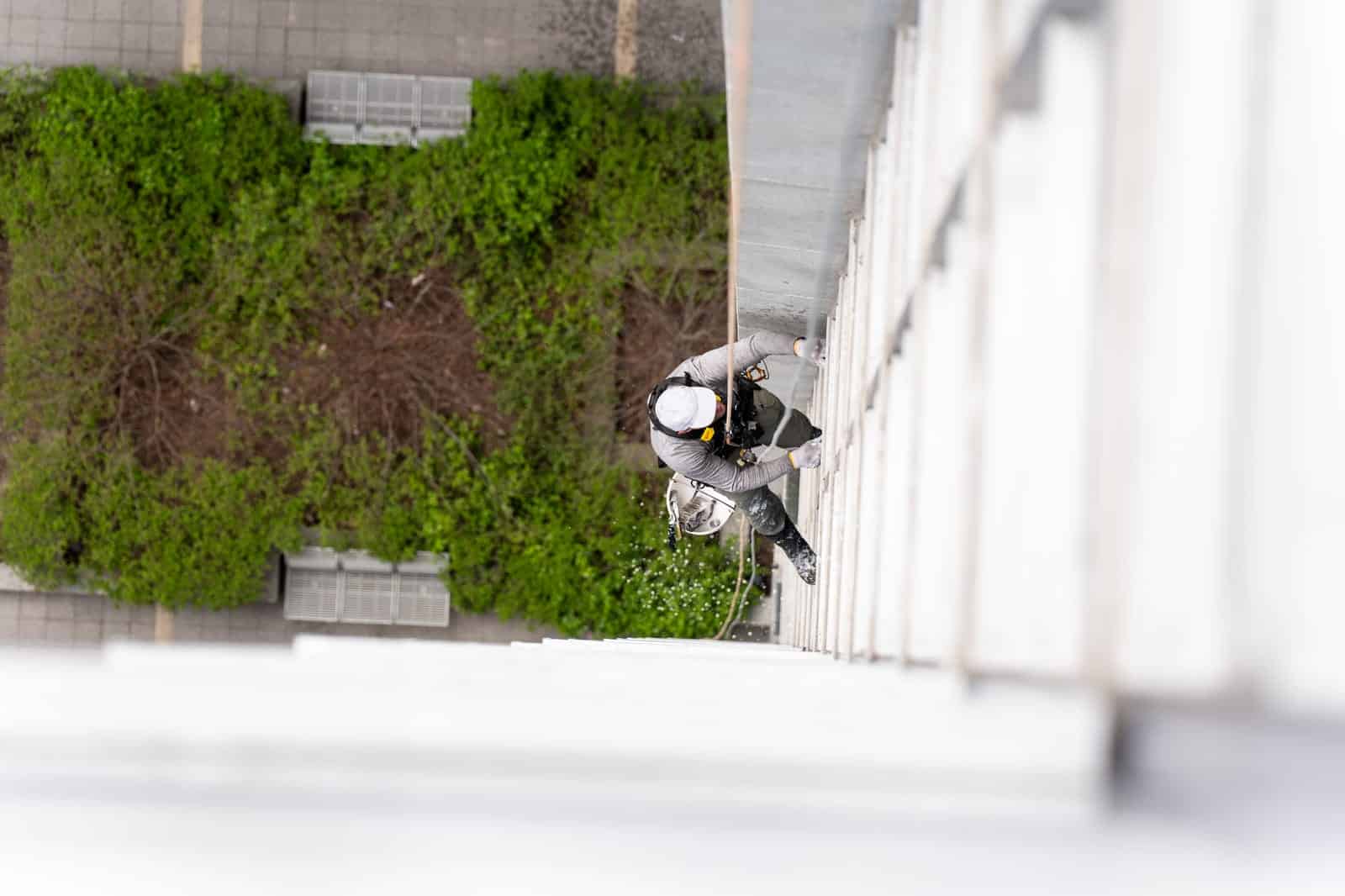 View from above of an industrial abseiler cleaning a window